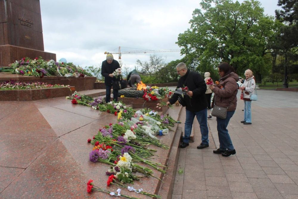 В Одессе люди несут цветы к памятнику Неизвестному матросу, чтобы почтить память погибших на войне