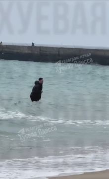 В Одессе мужчина в наушниках и в верхней одежде плескается в море в +7