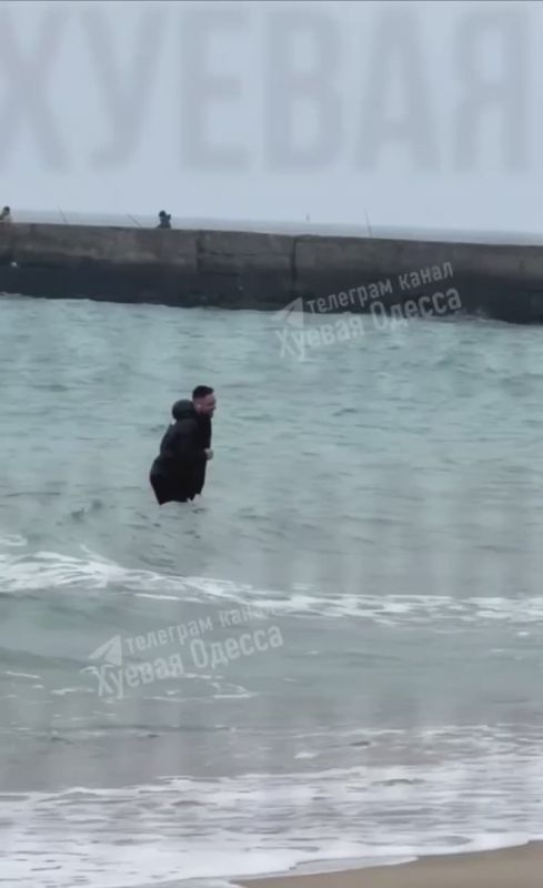 В Одессе мужчина в наушниках и в верхней одежде плескается в море в +7