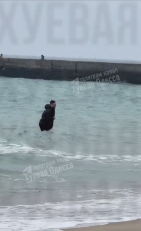 В Одессе мужчина в наушниках и в верхней одежде плескается в море в +7